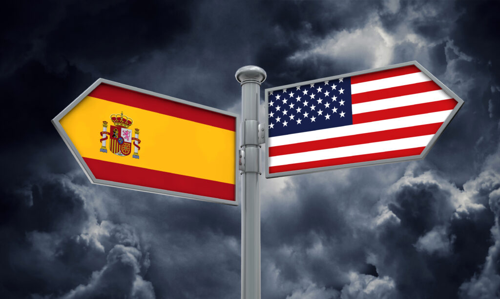 Banderas de España y EE. UU. en señales que apuntan en direcciones opuestas, símbolo del distinto rumbo regulatorio de la terapia con testosterona